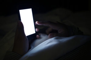 screen time on a smart phone in the dark lacking sleep