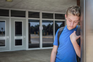 teenage boy at school looking sad depressed