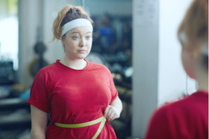 young woman struggling at gym with weight issues
