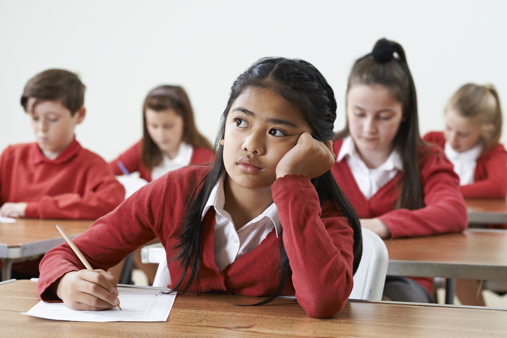 girl daydreaming or worried with occupied mind while in class in high school