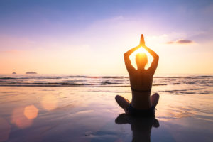teenage girl in yoga pose on beach at sunrise