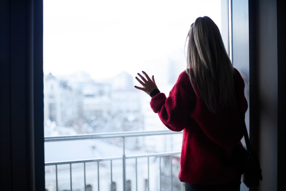 depressed girl looks out window at winter