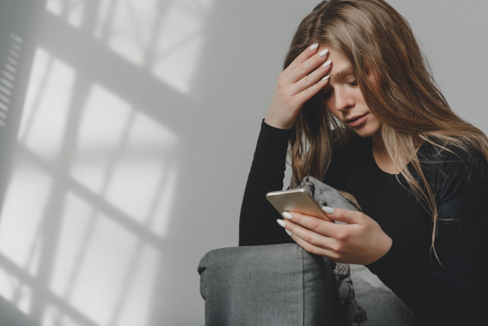 oung sad crying girl with a smartphone in her hand